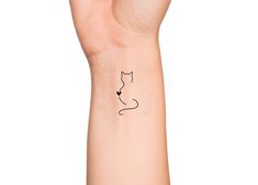 a hand with a small black cat tattoo on it's left arm and wrist