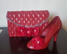 a pair of red high heeled shoes next to a handbag and purse on a table