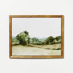 a painting hanging on the wall next to a white wall with a gold frame and an image of trees