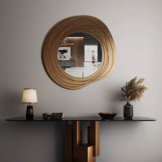 a mirror on the wall above a table with a vase and lamp next to it