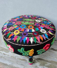 a colorfully decorated ottoman sitting on top of a wooden floor next to a wall