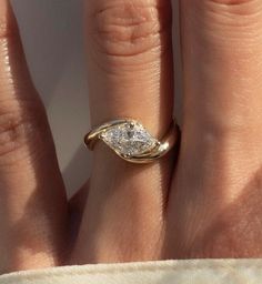 a close up of a person's hand with a diamond ring on their finger