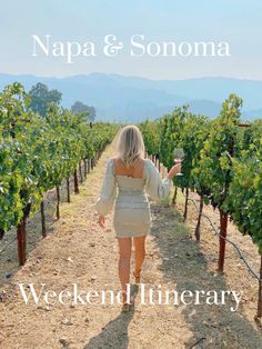 a woman walking down a dirt road holding a glass of wine in one hand and the words napa & sonna on the other