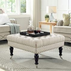 a living room filled with furniture and a tray on top of a coffee table in front of a window