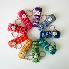 six crocheted keychains are arranged in a circle on a white surface