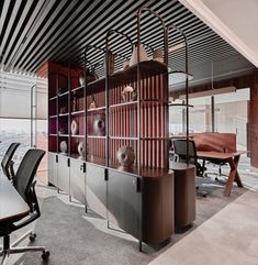 an office area with desks, chairs and shelves on the wall in front of large windows