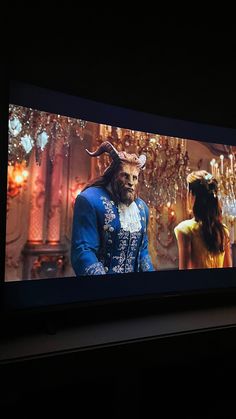 a large television screen with an image of a man and woman in costume on it