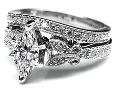 a wedding ring set with a pear shaped diamond in the center and side stones on each band