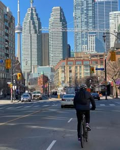 a bicyclist is riding down the street in front of tall buildings