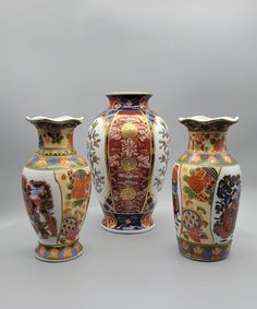 Elevate your decor with this exquisite set of three vases, each boasting intricate hand-painted details and radiant gold accents. The centerpiece is a majestic Japanese Gold Imari Porcelain Vase, circa 1970s, crafted by Arita Bussan Co., Ltd. with impeccable artistry. Standing 7 inches tall and 4.5 inches in diameter, it features a mesmerizing oriental floral design delicately rendered on white porcelain, enhanced by lavish gold gilt accents and a graceful gold rim border. Impeccably preserved, Chinoiserie Home, Imari Porcelain, Hand Painted Vases, Home Decor Vintage, Gold Highlights, Ceramic Vases, Vase Set, Large Vase, Small Vase