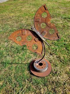 a rusted metal object sitting on top of a grass covered field