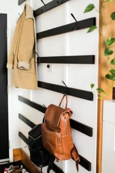 a backpack hanging on a wall next to a coat rack with shoes and purses