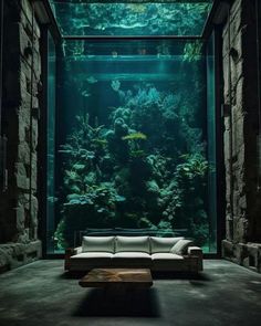 a living room filled with lots of green plants next to a large fish tank on top of a stone wall