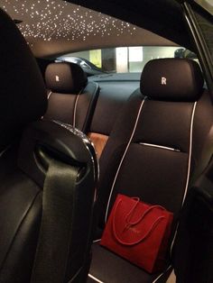 the interior of a car with black leather seats and red handbags on the floor