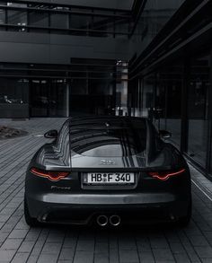 a black sports car is parked in front of a building with its license plate on