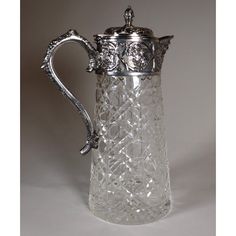 an ornate glass pitcher with a silver handle