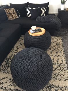 a living room filled with black furniture and pillows on top of a carpeted floor