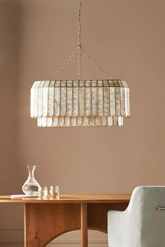 a chandelier hanging from the ceiling over a wooden table with two white chairs