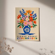 a flower market sign hanging on the wall next to a vase with flowers in it