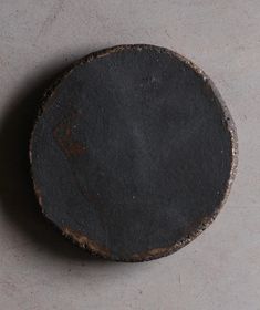 an old round black object sitting on top of a cement floor next to a wall