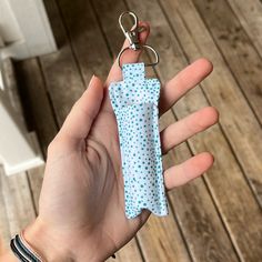 a hand holding a blue and white polka dot umbrella keychain on it's thumb