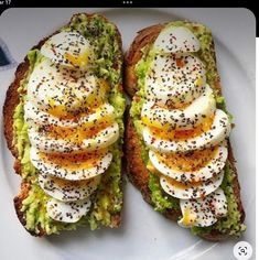 two pieces of bread with eggs and other toppings on it sitting on a plate