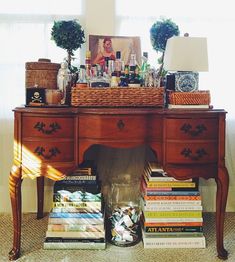 a table with many books and vases sitting on it's top, in front of a window