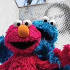 two sesame street characters standing next to each other