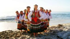 a group of young women standing on top of a sandy beach next to the ocean