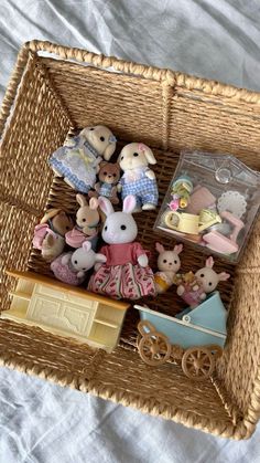 a wicker basket filled with lots of small toy animal figurines on top of a bed