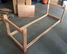 a wooden bed frame sitting on top of a floor next to plywood planks