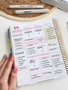 a person's hand on top of a planner next to some markers and pencils