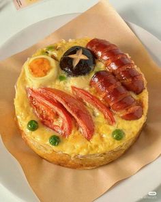 a breakfast pastry with bacon, eggs and ham on it sitting on top of a white plate