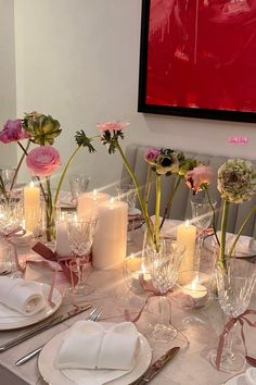 the table is set with candles and flowers in vases, plates and napkins