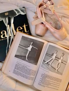 an open book and ballet shoes on a bed