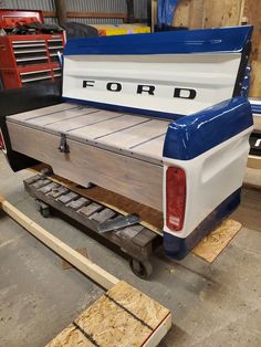 the back end of a blue and white truck with wood planks on it's floor