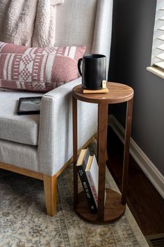 a coffee cup on a table in front of a couch with pillows and a book