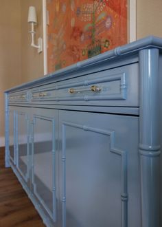 a large blue cabinet in a room with wood flooring and paintings on the wall