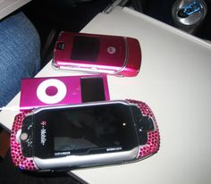 two cell phones sitting next to each other on top of a white table with pink beads