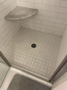 a bathroom with a shower stall and tiled flooring in the corner, along with a rug on the floor