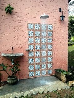 an outdoor shower in front of a pink wall with blue and white tiles on it