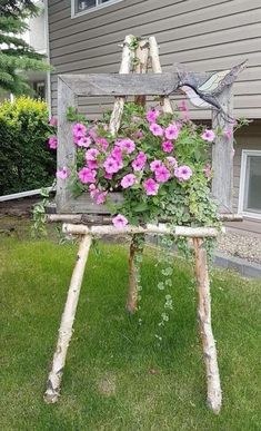 an old chair with flowers growing out of it in front of a house on the grass