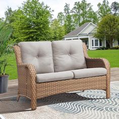 a wicker couch sitting on top of a patio next to a potted plant