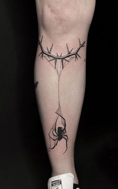 a man's leg with barbed wire and spider on it