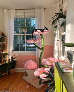 a room with pink flowers and plants in the windowsill, along with a cat tree