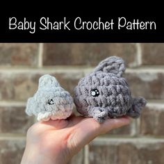 two small crocheted animals are held in front of a brick wall with the words baby shark crochet pattern