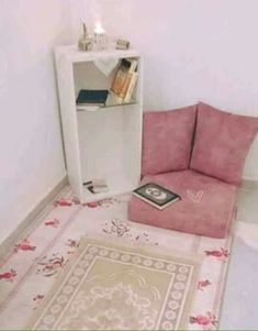 a pink chair sitting next to a book shelf in a room with flowers on the floor