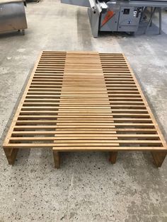 a wooden bed frame sitting on top of a floor in a room filled with machines