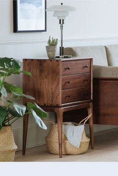 a wooden dresser sitting next to a plant in a living room