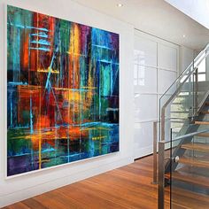 an abstract painting hangs on the wall next to a stair case in a modern home